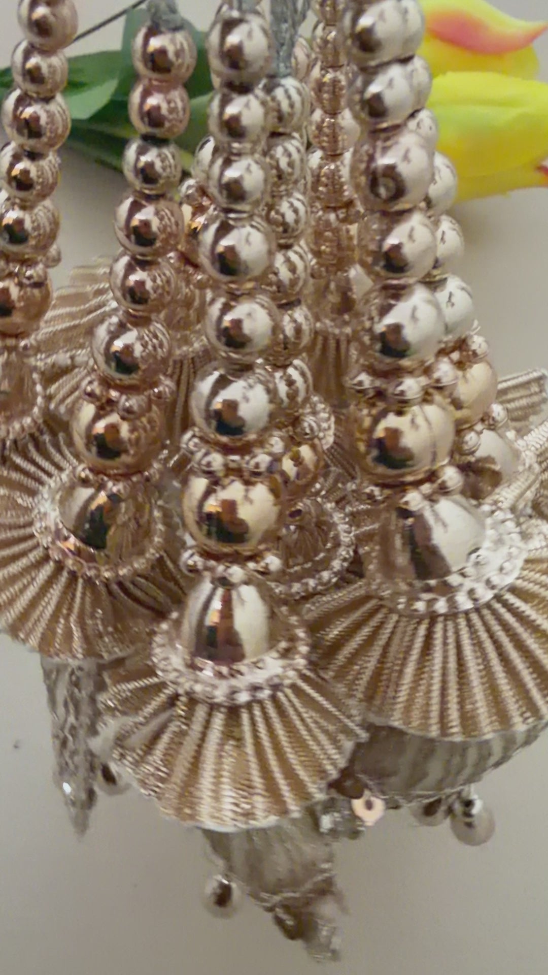 Decorative hanging charm next to a ruler on a beige background