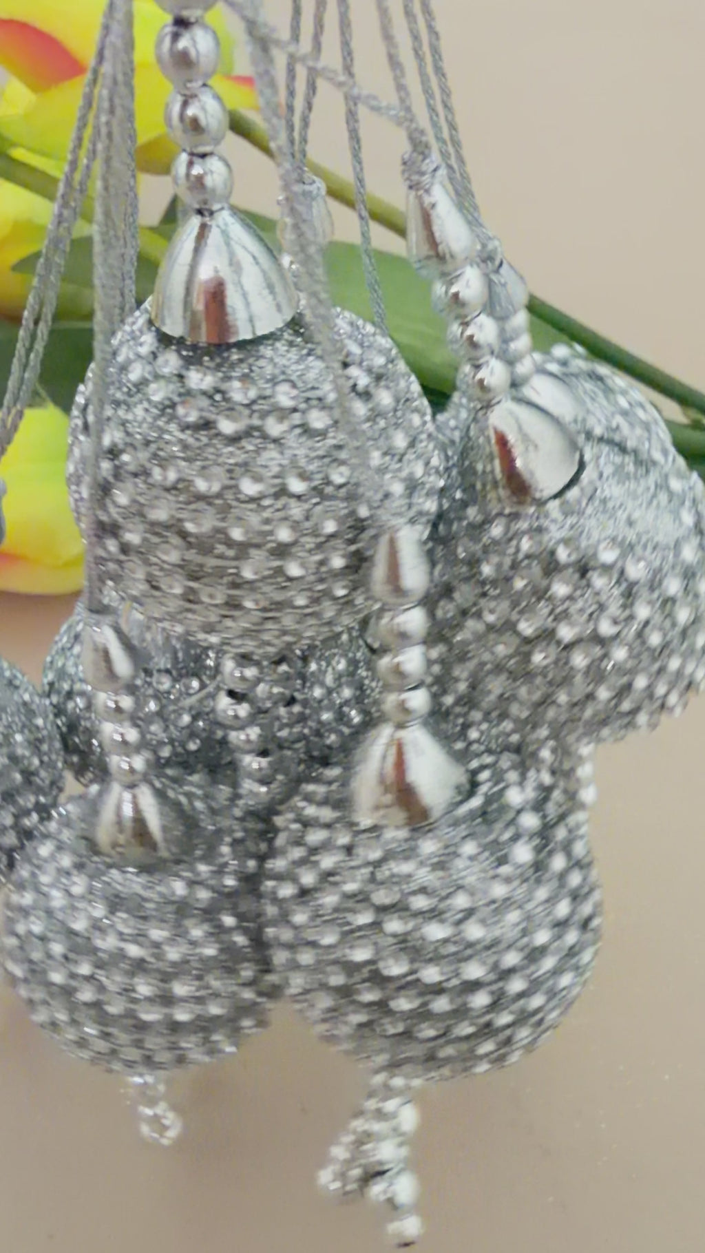 Silver beaded decorative item held in a hand with a blurred background