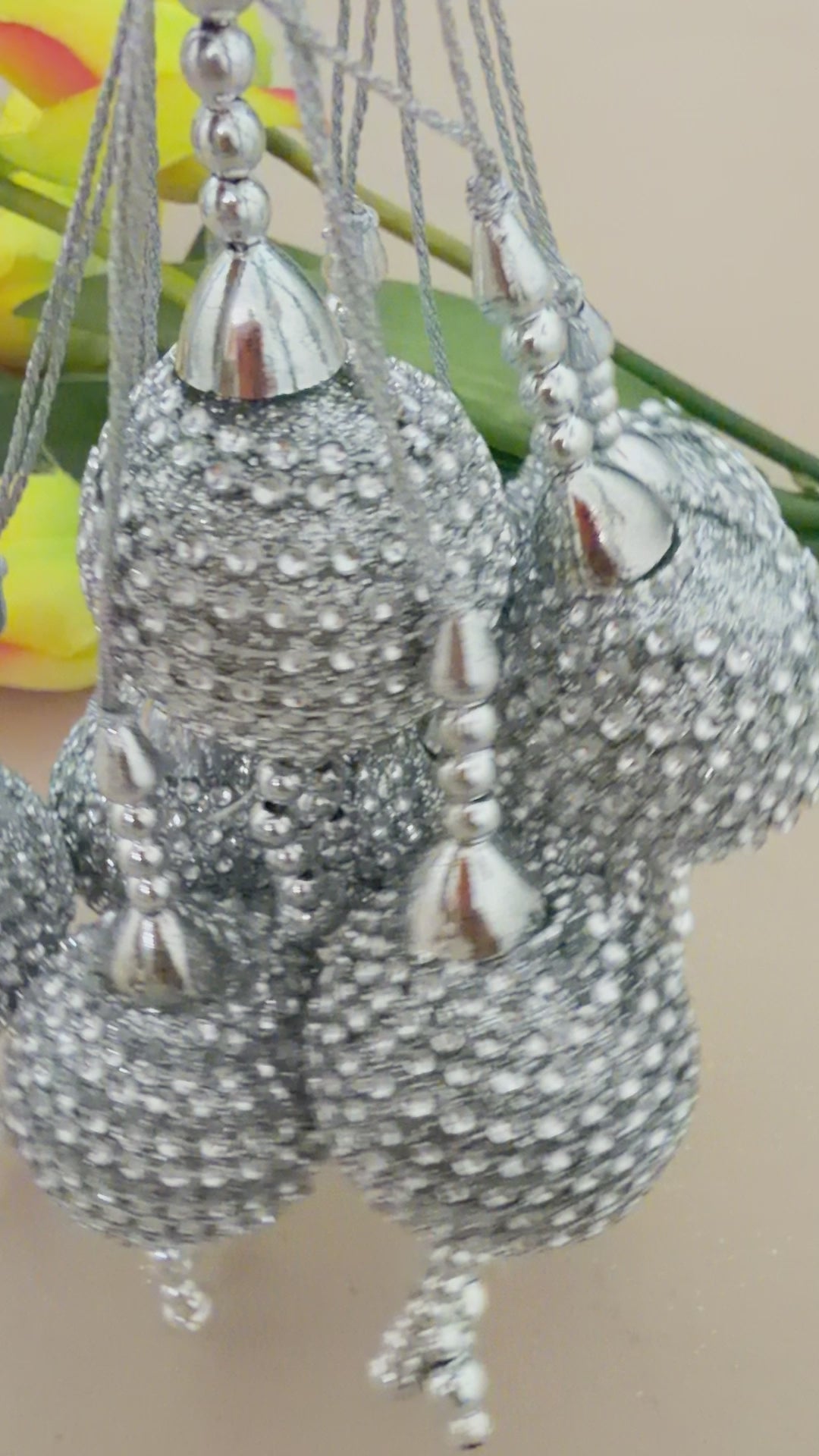 Silver beaded decorative item held in a hand with a blurred background