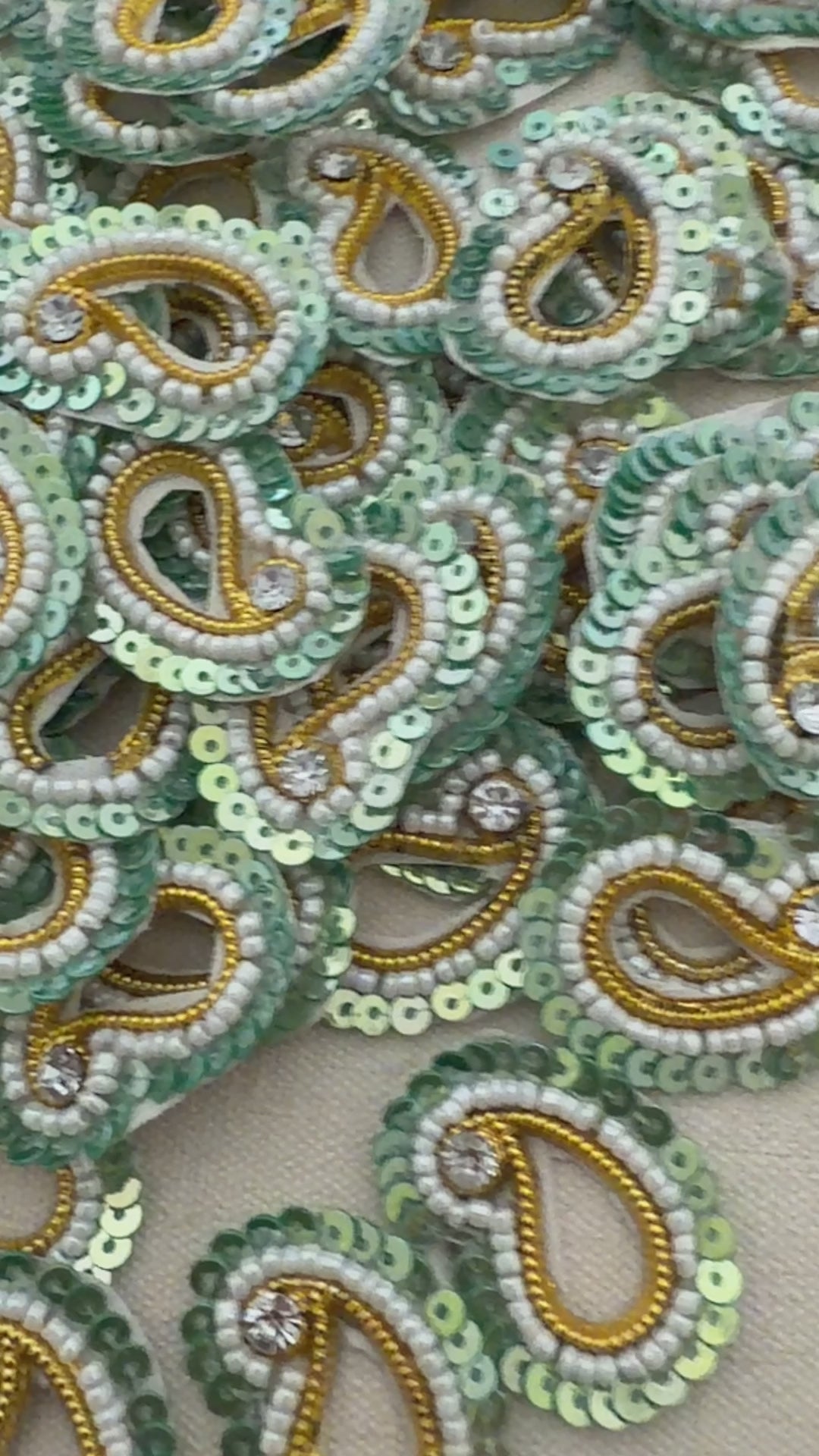 Collection of green and gold beaded paisley designs on a beige background