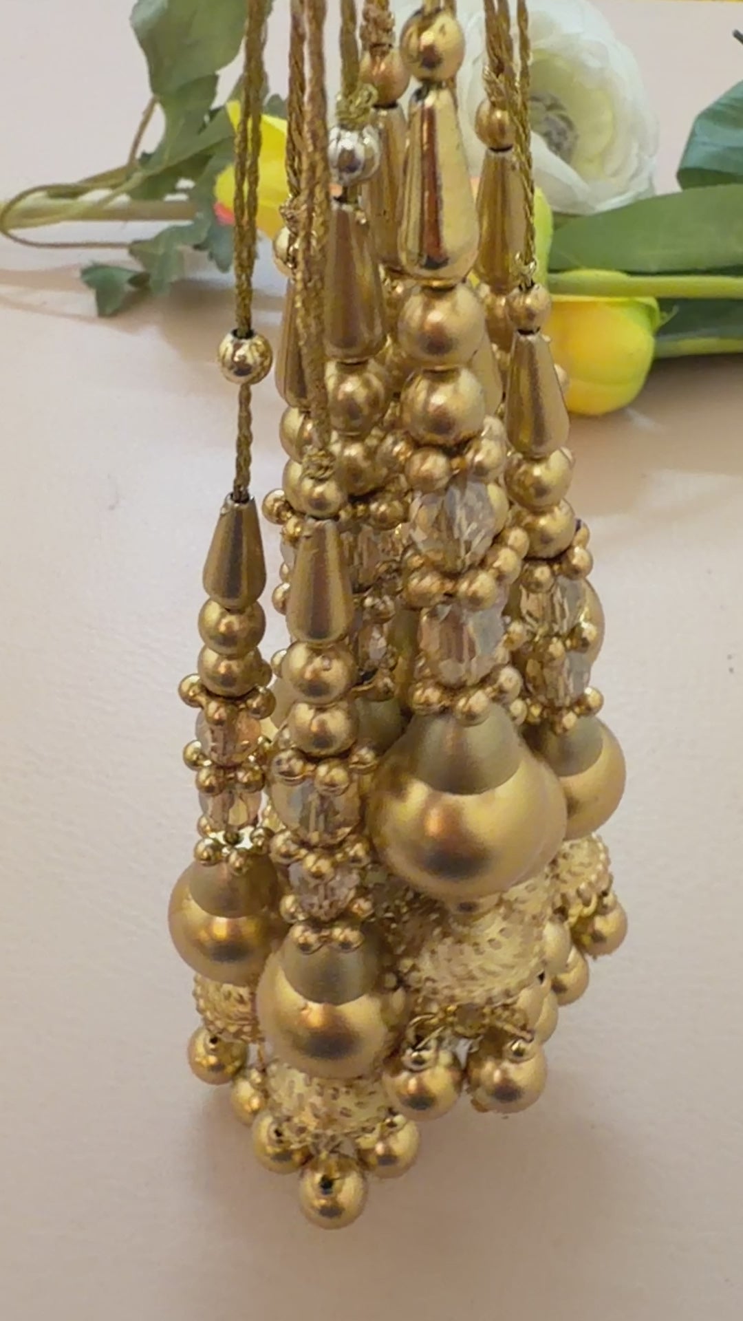 Gold earrings with spherical beads and intricate designs on a light gray background
