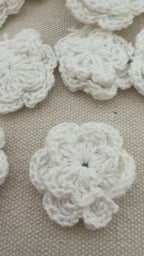 White crocheted flower with a measurement label on a beige background