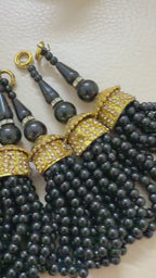 Set of black beaded tassels with gold accents on a beige background