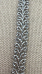 Spool of silver lace fabric on a beige background
