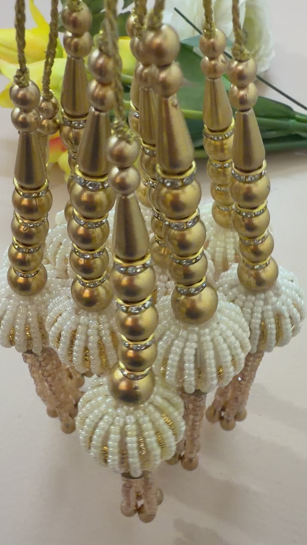 Decorative hanging beads with gold and beige colors on a white background