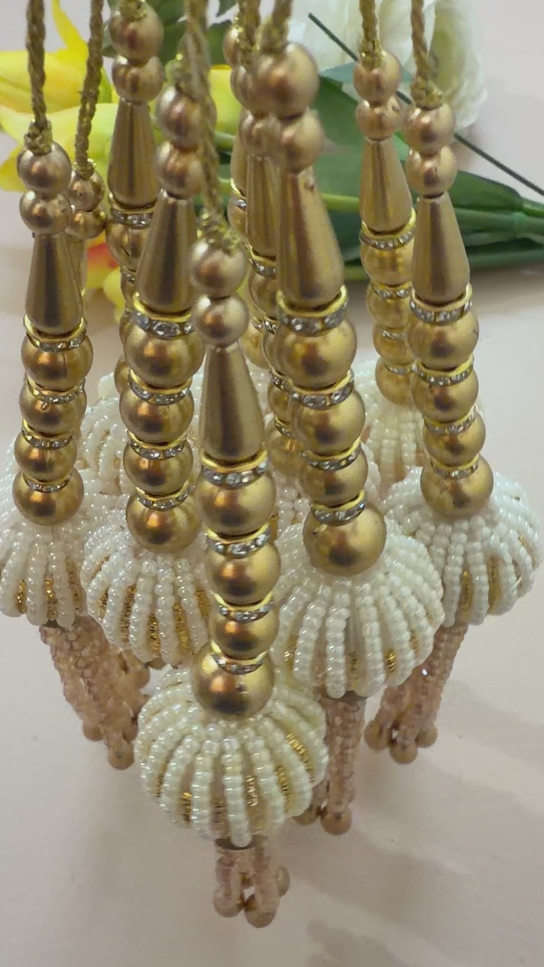 Decorative hanging beads with gold and beige colors on a white background
