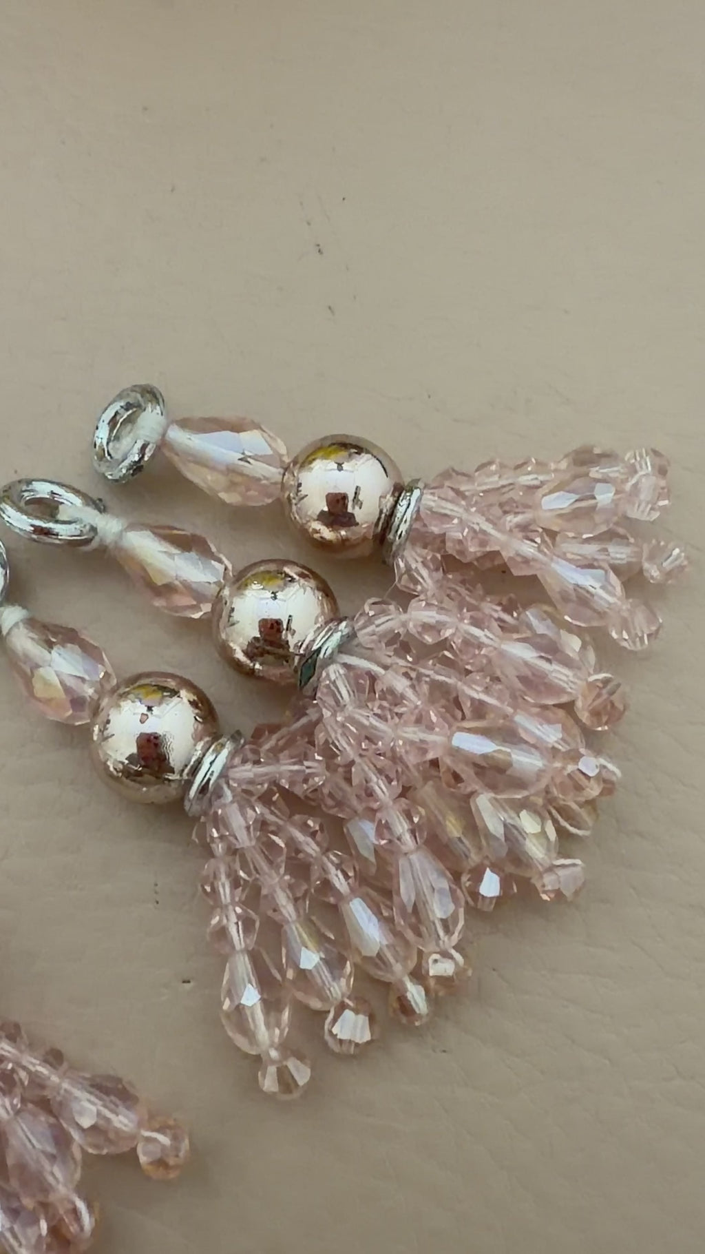 Beaded charms with pink and gold beads on a beige background