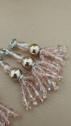 Beaded charms with pink and gold beads on a beige background