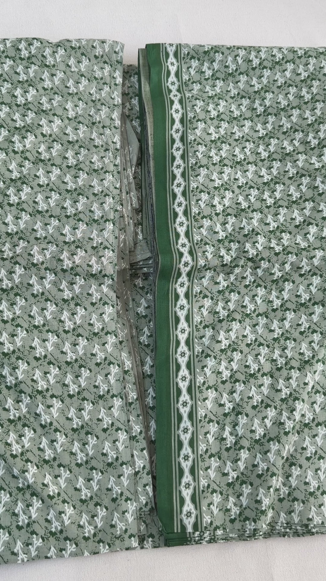 Fabric with a pattern of white and green shapes on a gray background