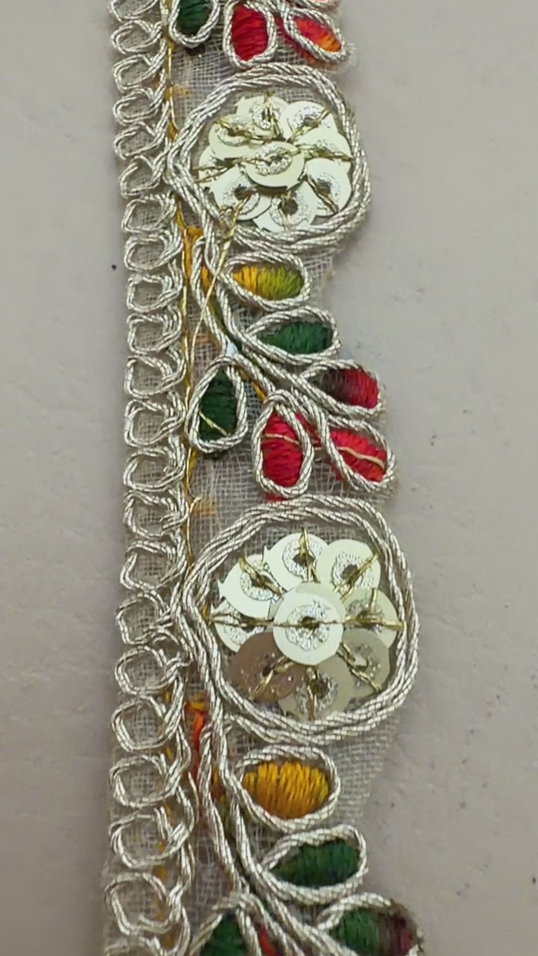 Decorative lace trim held between fingers with a neutral background