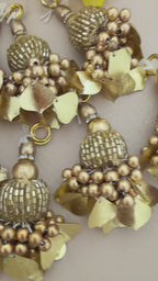 Decorative gold wreath with spherical beads and leaf-like elements on a light gray background