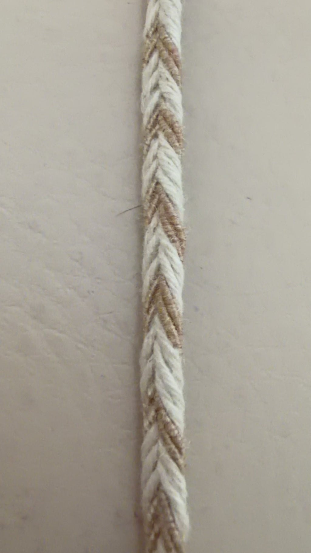 Measuring tape showing the thickness of a braided rope on a beige background