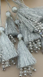 Silver tassels with beads on a beige background with yellow flowers