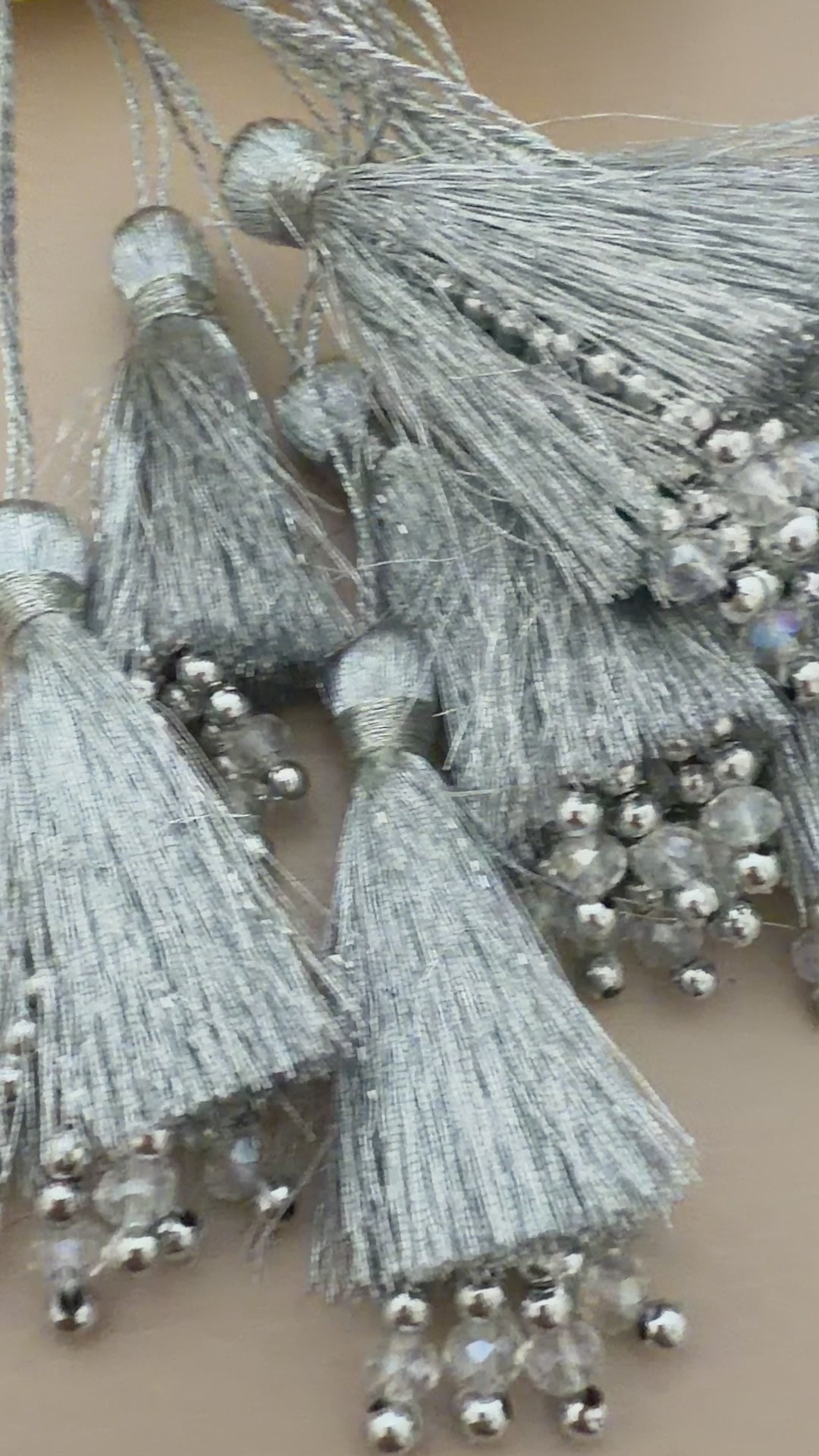 Silver tassels with beads on a beige background with yellow flowers