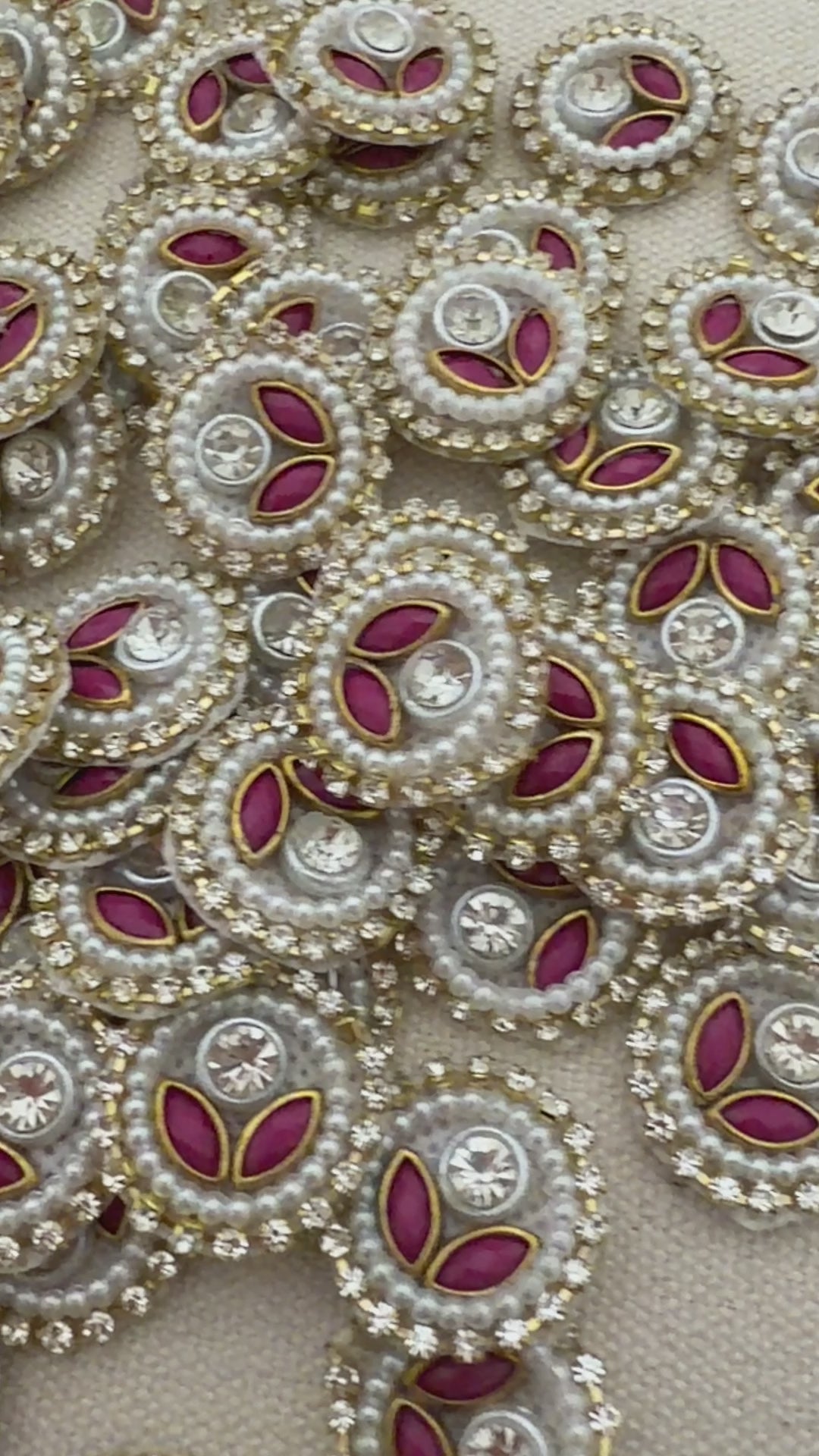 Close-up of decorative elements with pearls, red stones, and gold accents on a beige background