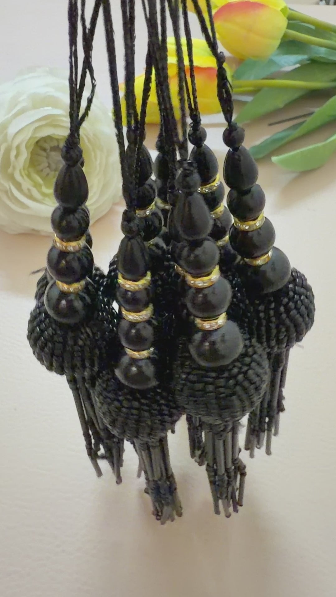 Black beaded tassel necklace on a light gray background