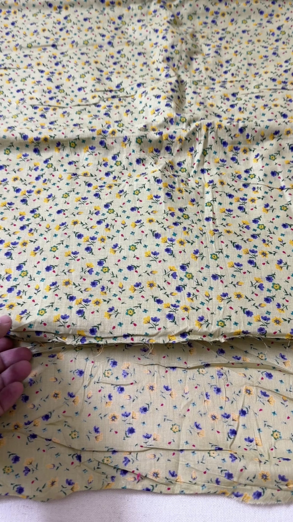 Floral fabric with small flowers in blue, yellow, and purple on a beige background