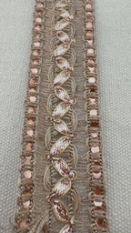 Decorative headband with rose gold accents on a neutral background with a white flower.