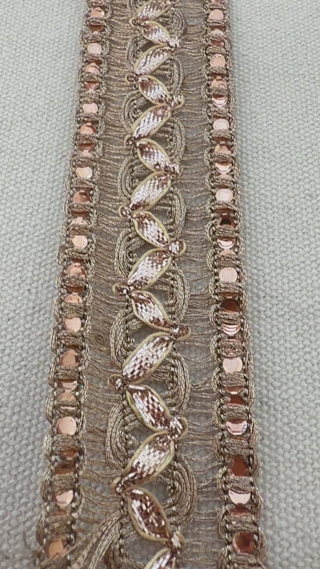 Decorative headband with rose gold accents on a neutral background with a white flower.