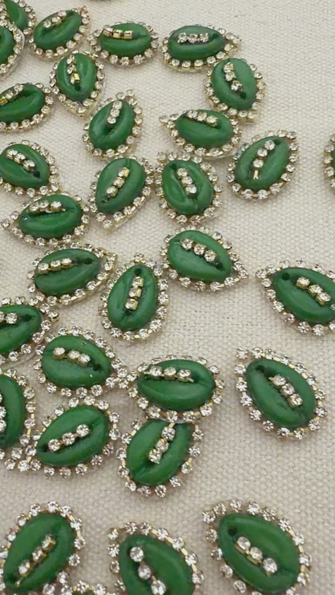 Green leaf-shaped buttons with rhinestone accents on a textured beige background
