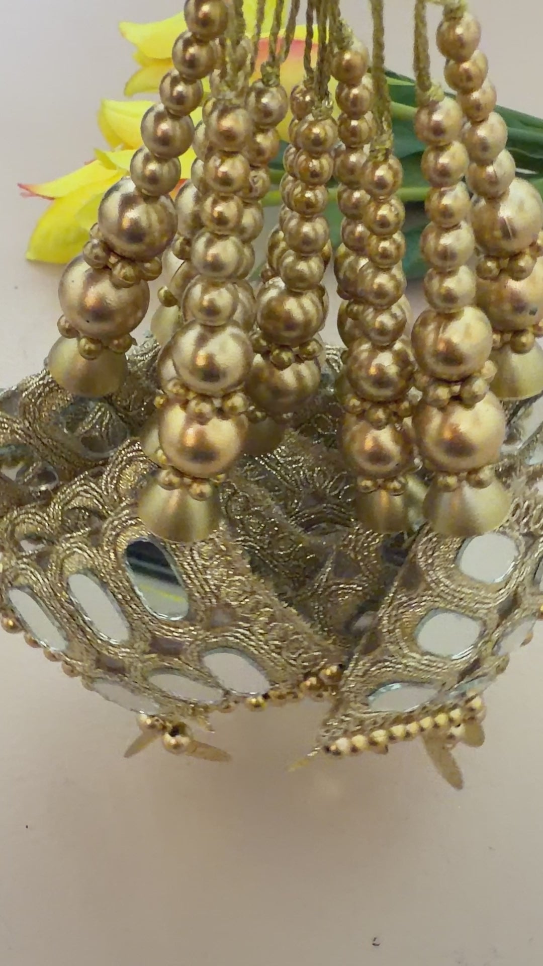 Decorative gold hair accessories with mirror details on a beige background with yellow flowers.
