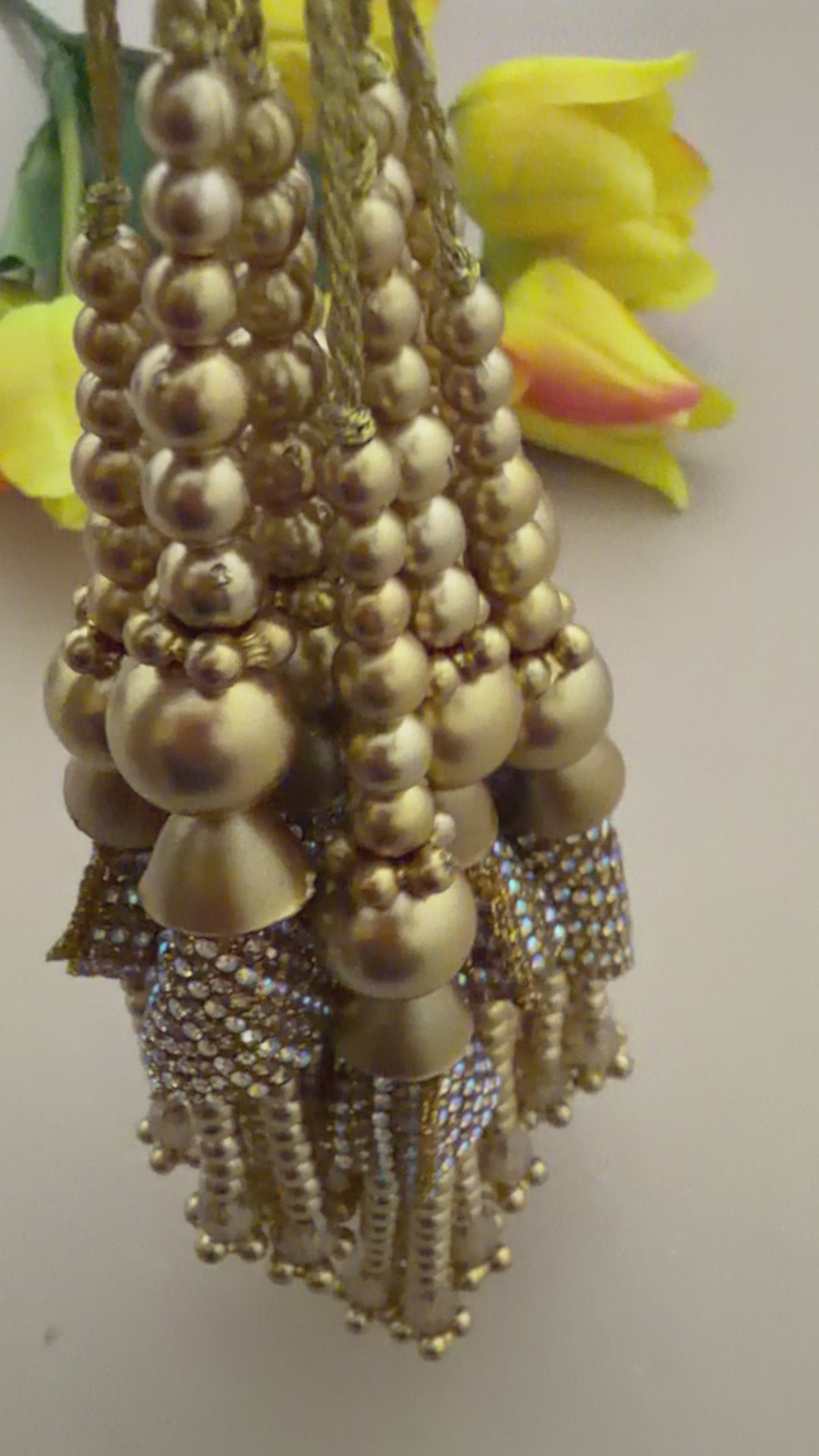 Decorative hair accessories with pearls and gold elements next to yellow tulips 