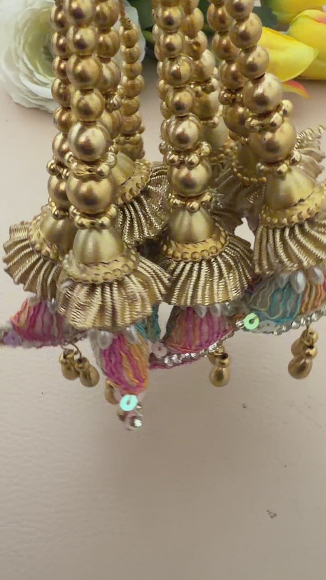 Decorative hair accessories with gold beads and colorful tassels on a neutral background