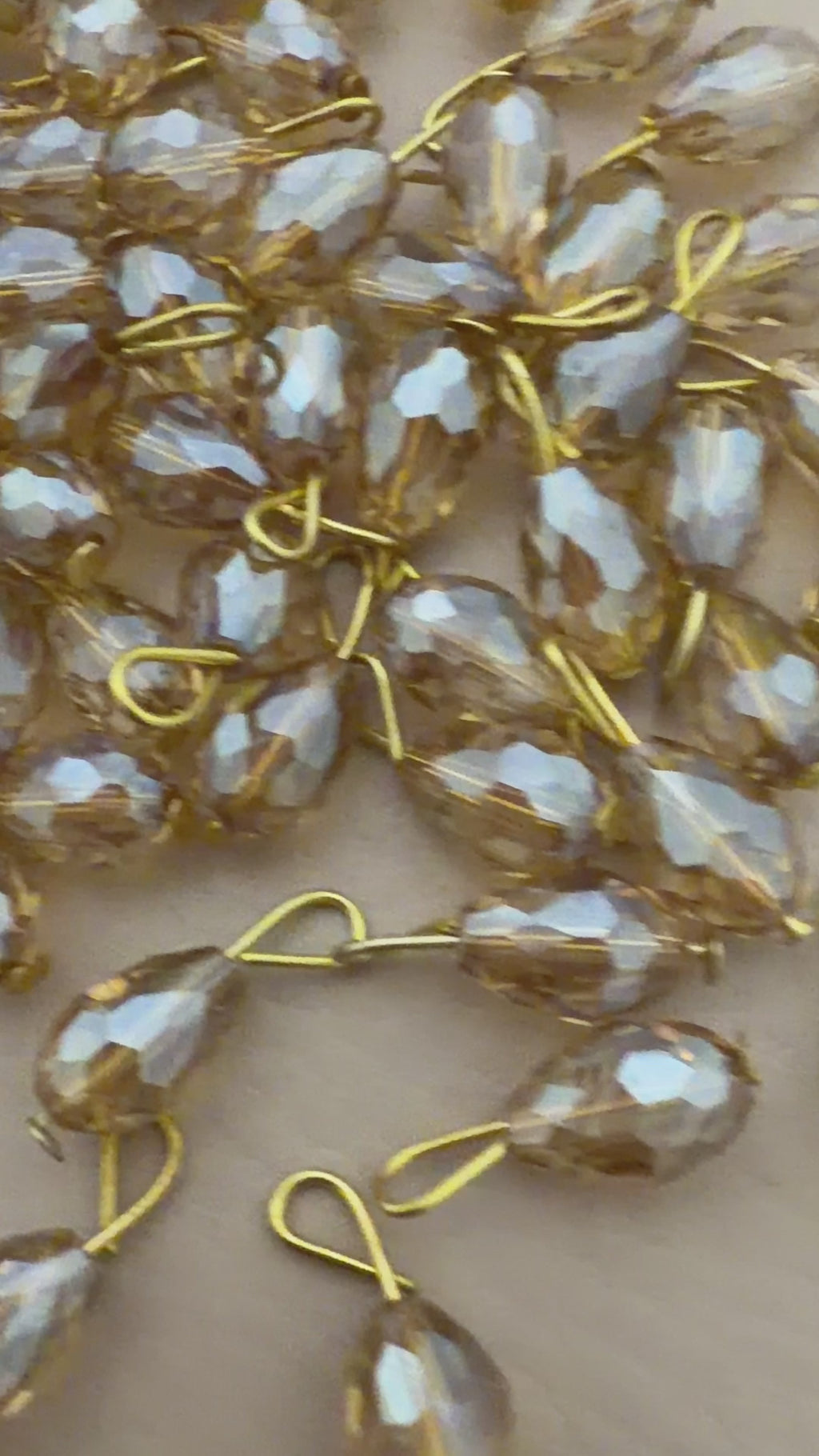 Gold and silver teardrop-shaped jewelry components on a beige background