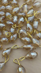 Gold and silver teardrop-shaped jewelry components on a beige background