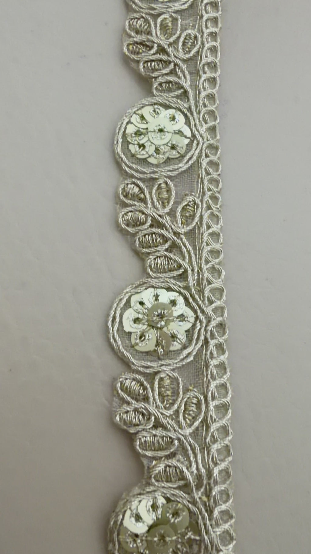 Decorative headband with intricate lace design on a white rose background