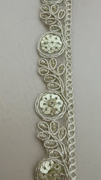 Decorative headband with intricate lace design on a white rose background
