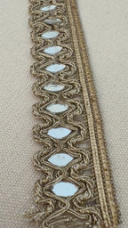 Decorative lace trim with reflective stones on a beige fabric background