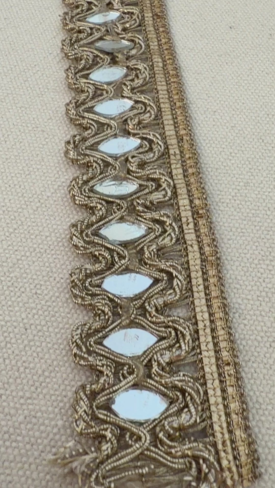 Decorative lace trim with reflective stones on a beige fabric background