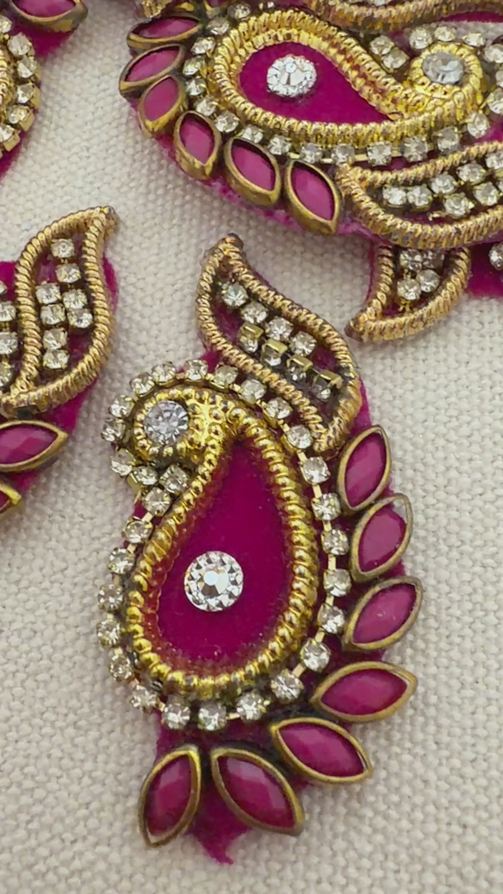 Decorative pink and gold earrings with gemstones on a light background