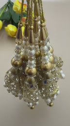 Decorative hair accessories with pearls and gold elements next to yellow tulips on a light pink background