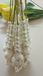 Pearl and gold tassel earrings on a beige background