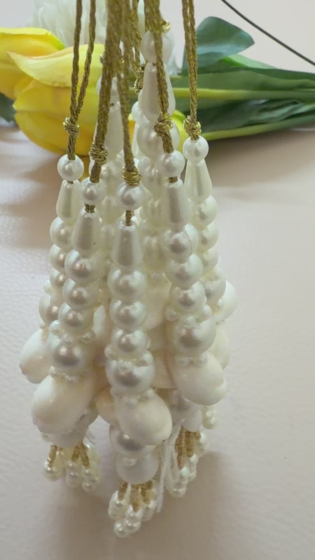 Pearl and gold tassel earrings on a beige background
