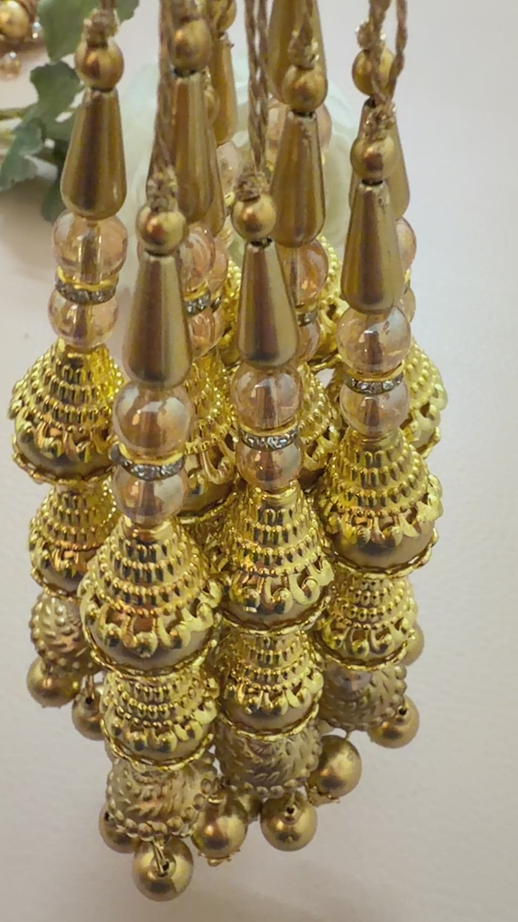 Close-up of a gold necklace with pearl-like beads on a light background