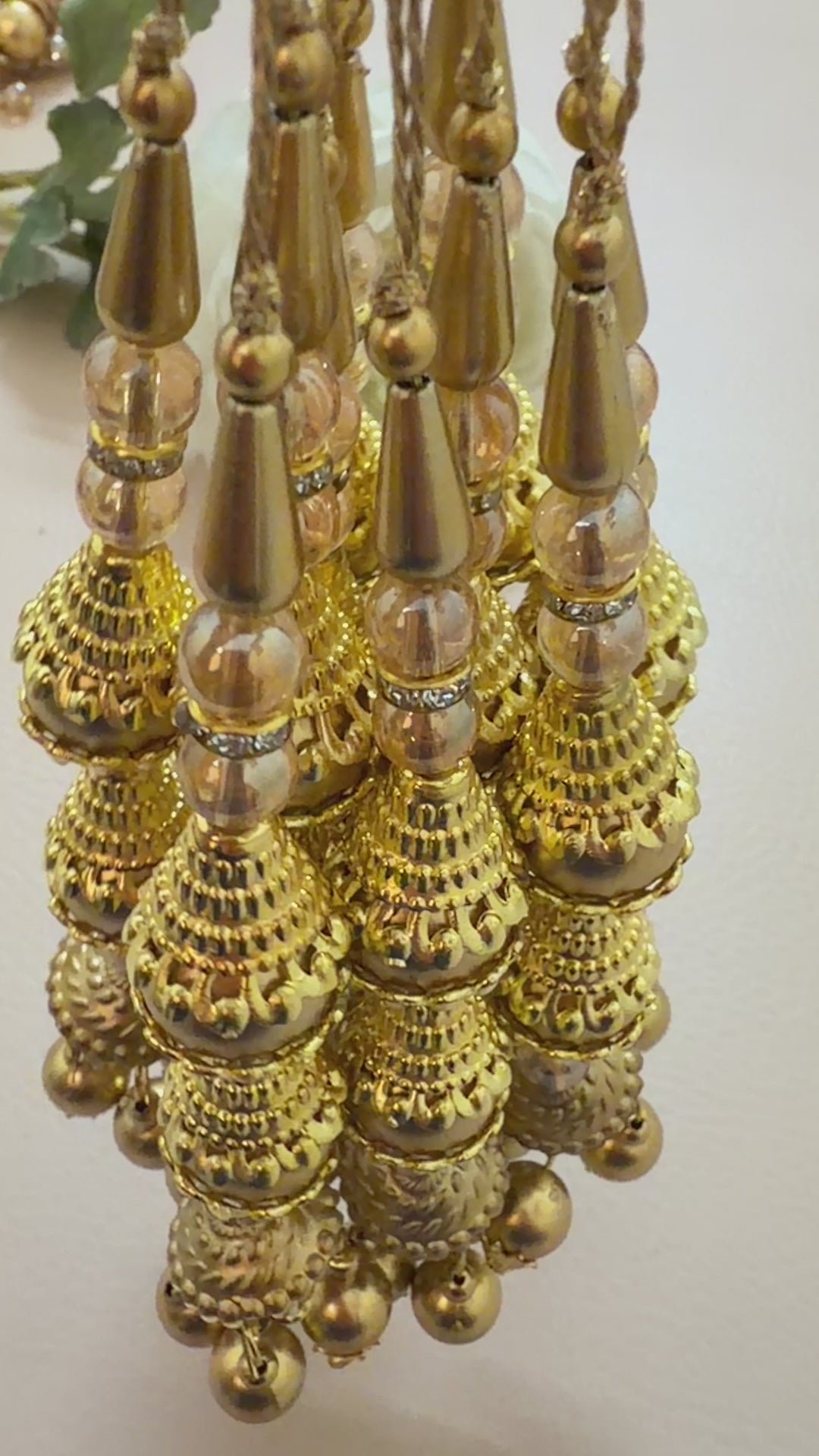 Close-up of a gold necklace with pearl-like beads on a light background