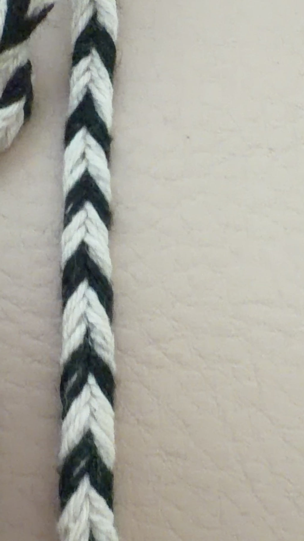 Spool of black and white striped rope on a beige background