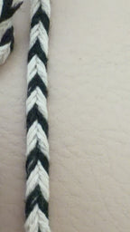 Spool of black and white striped rope on a beige background