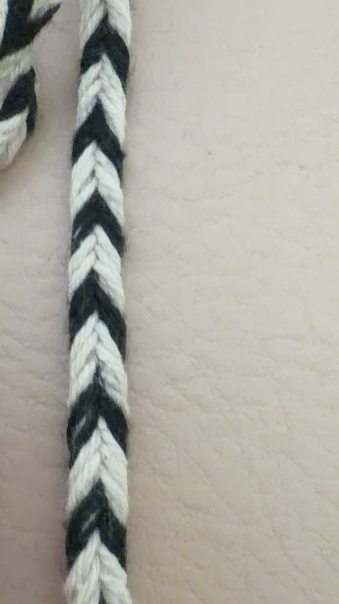 Spool of black and white striped rope on a beige background
