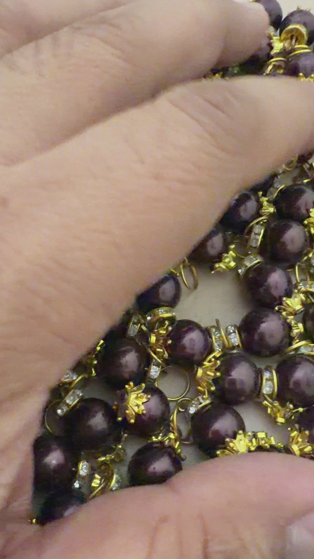 Close-up of a bracelet with purple beads and gold accents on a light background