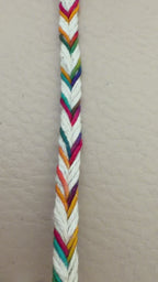 Spool of colorful zigzag-patterned rope on a beige background