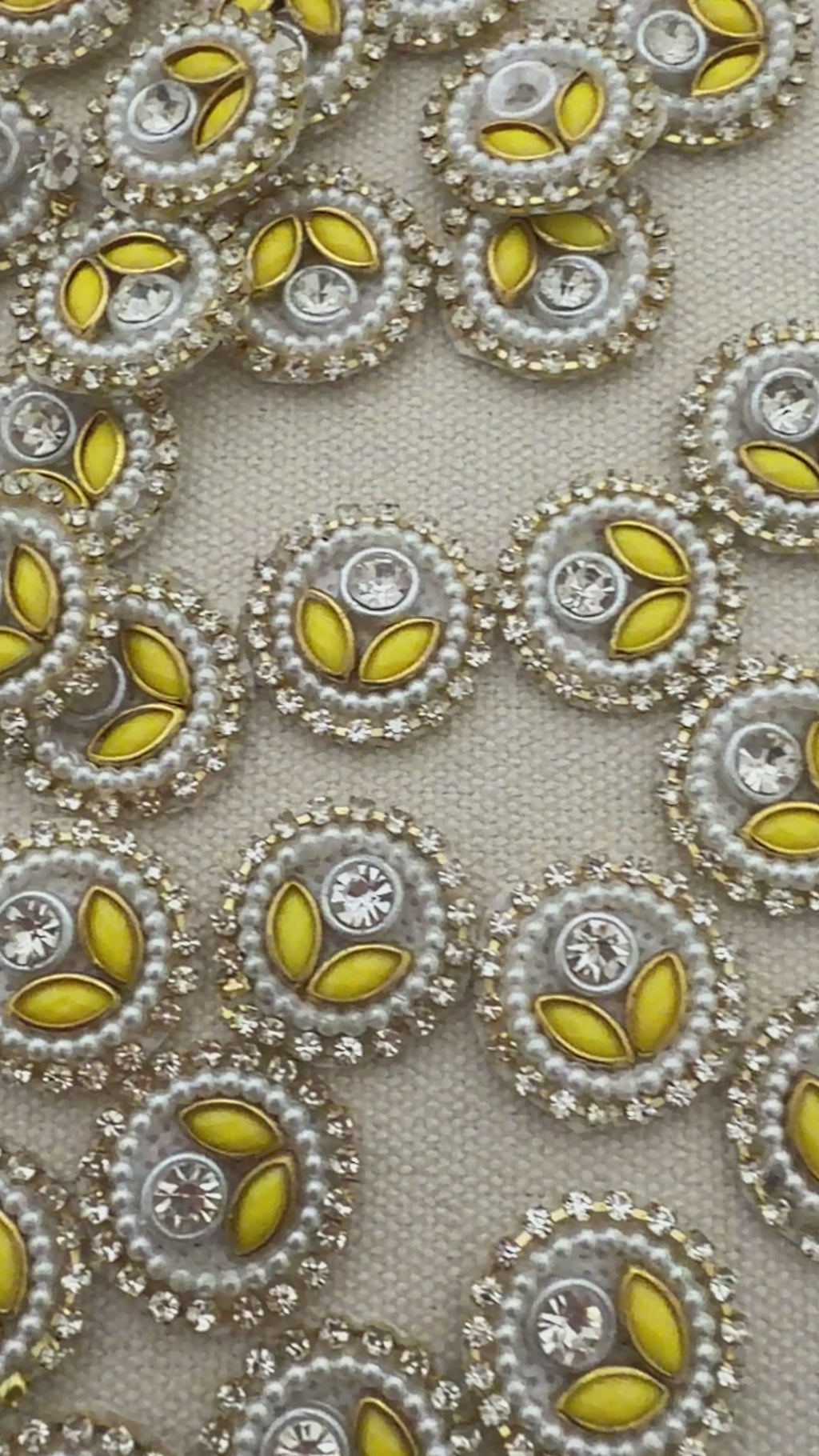 Close-up of decorative buttons with yellow centers and pearl-like borders on a light gray background