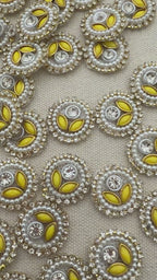Close-up of decorative buttons with yellow centers and pearl-like borders on a light gray background