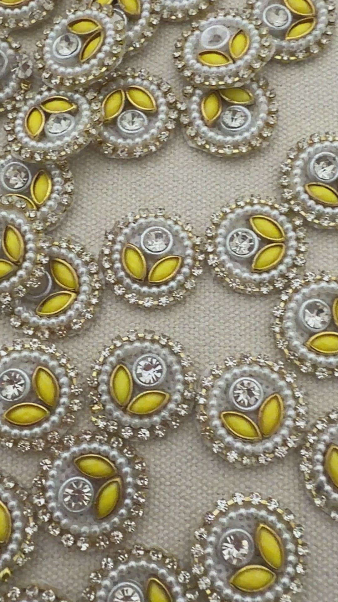 Close-up of decorative buttons with yellow centers and pearl-like borders on a light gray background