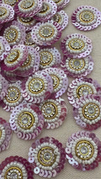 Sequined embellishments with pink, gold, and white colors on a beige background