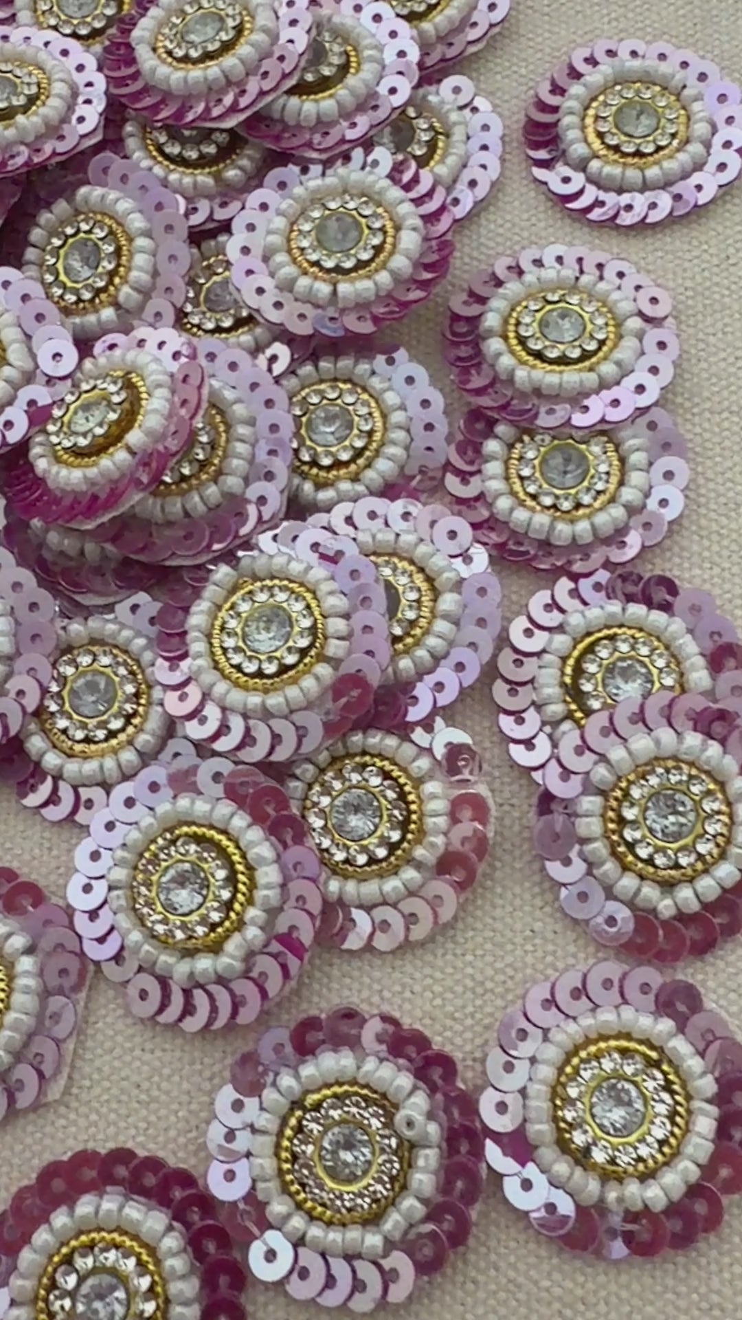 Sequined embellishments with pink, gold, and white colors on a beige background