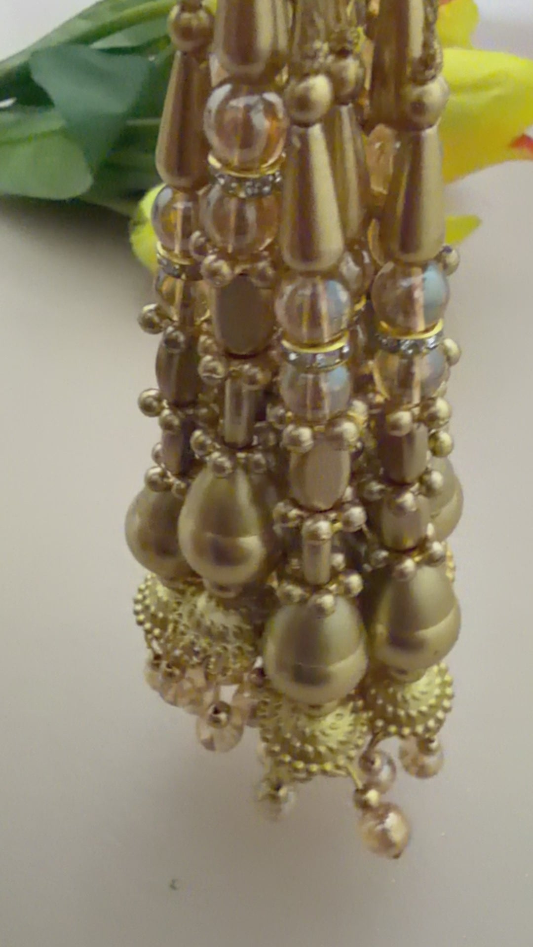 Gold jewelry with pearl accents on a light background with yellow flowers.